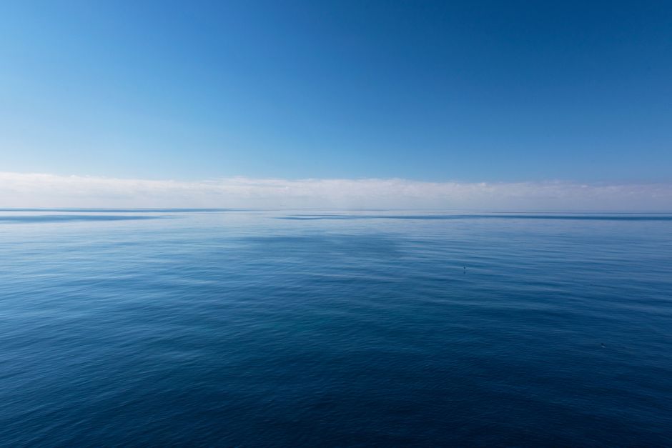 A serene ocean view with a clear blue sky and calm waters, evoking peace and tranquility.